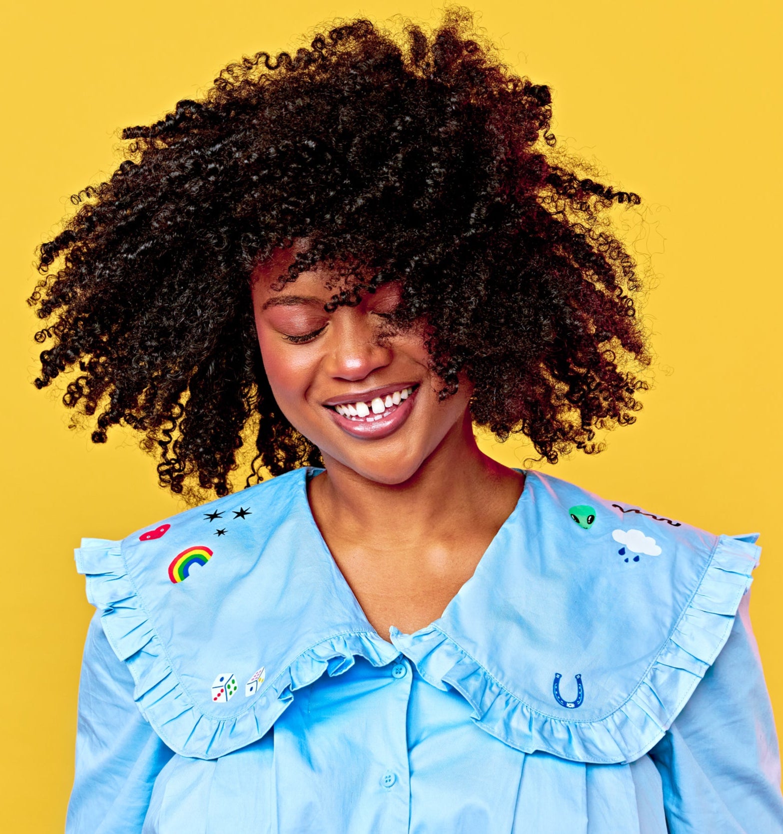 Woman wearing a blue shirt with custom patches designs on a yellow background